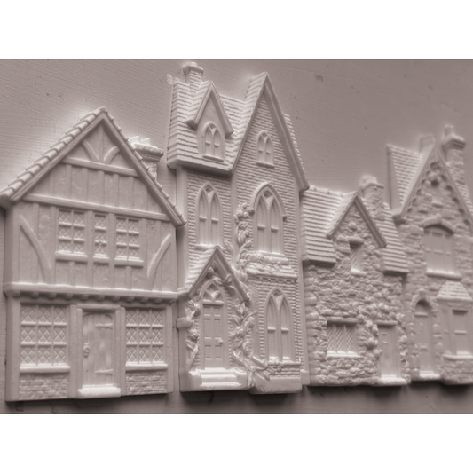 Unpainted castings of houses with detailed medieval and cottage architecture, shown on a plain light background.