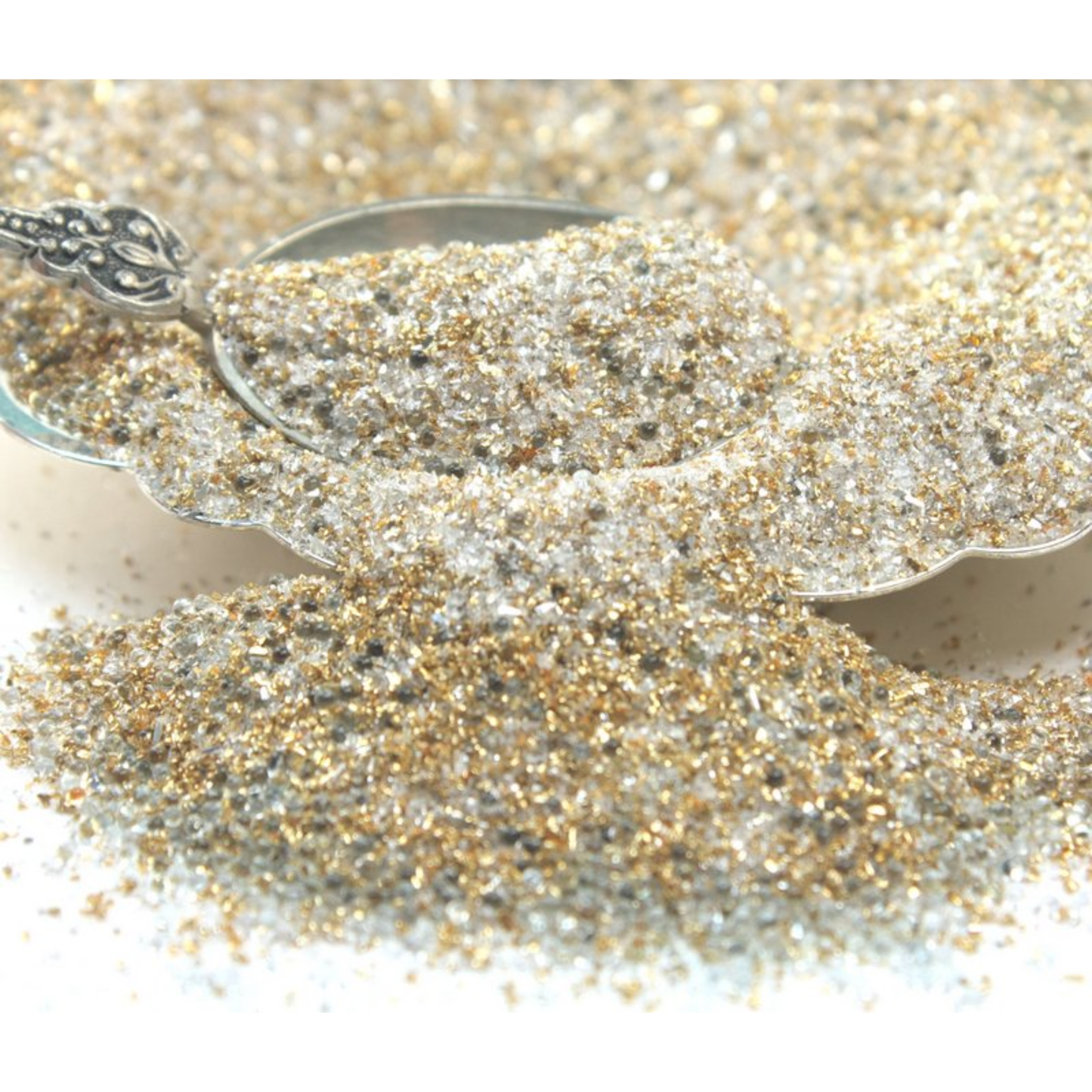 Silver spoon with gold and silver glitter on a white background