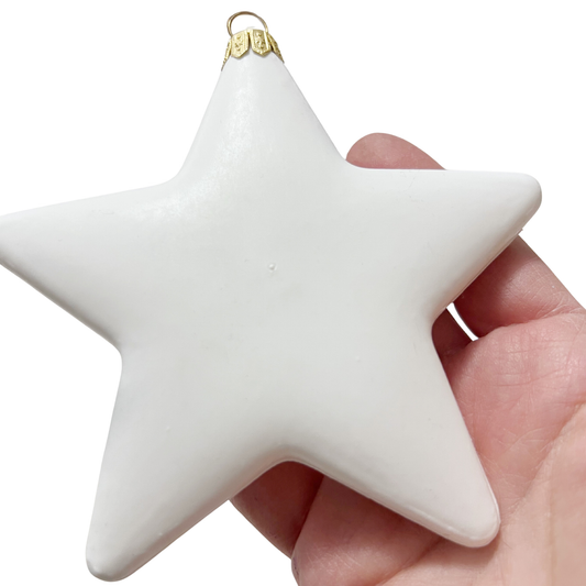 White star-shaped ornament held in a hand against a white background