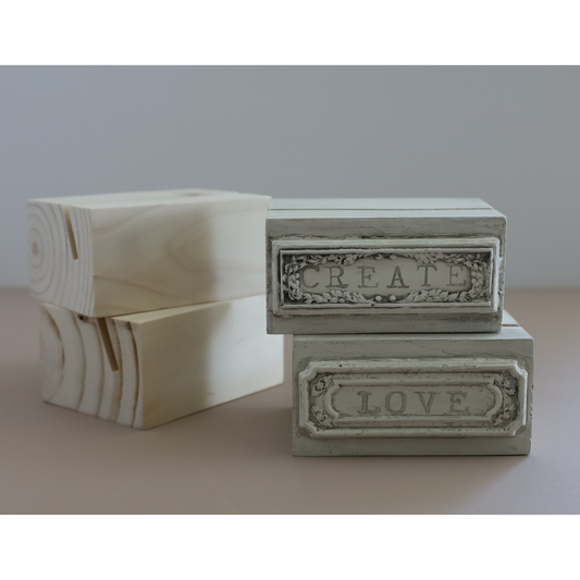 Four rectanglular wooden boxes; Two rectangular decorative including two stacked natural wood boxes and two distressed off-white boxes/blocks labeled CREATE and LOVE, on a neutral surface.
