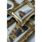 A close-up of ornate gold picture frames with carved decorative details, some containing painted architectural scenes, arranged on a light background.