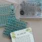 A collage of mini stamp sheets  from Iron Orchid Designs' 'A Timely Tale' collection, featuring various decorative designs in light gray and teal-blue tones on a white background.