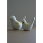 Two white ceramic bird-shaped candle holders with gold image transfer accents, standing side by side on a neutral surface against a gray background.
