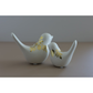 Two white ceramic bird figurines with gold image transfer pinecone designs, displayed on a neutral beige surface against a gray background.