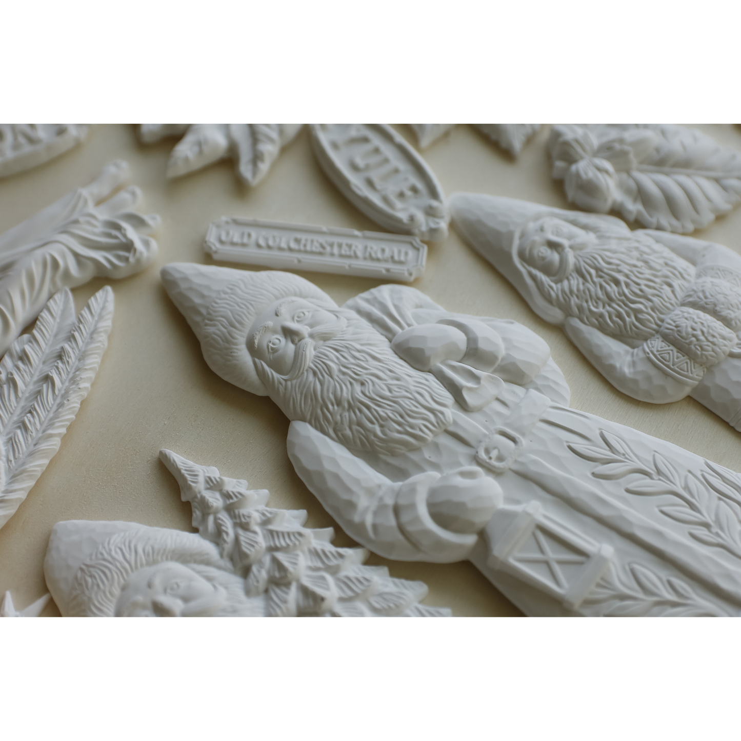 Castings example of IOD Mould Belsnickel, featuring white Christmas ornaments and decorative cutouts arranged on a light beige background, including a figurines, a Christmas tree, and holiday motifs.