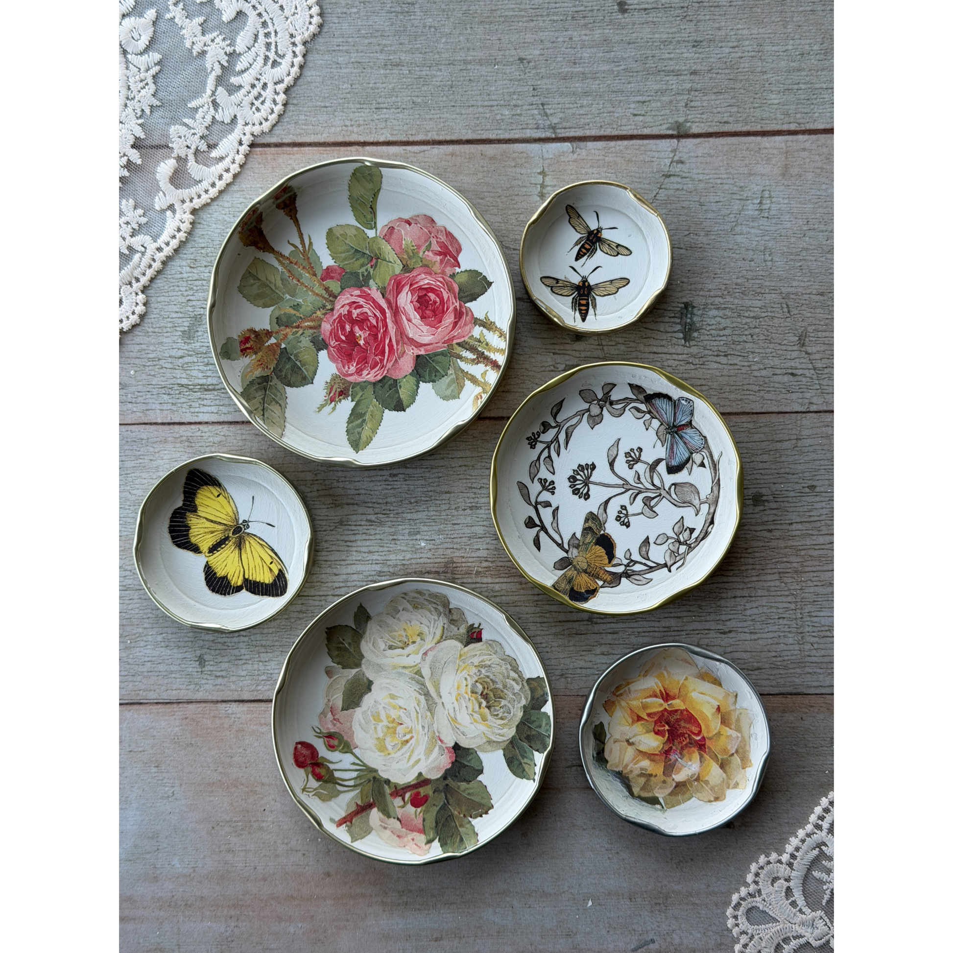 Set of decorative plates with floral and butterfly designs on a wooden surface.