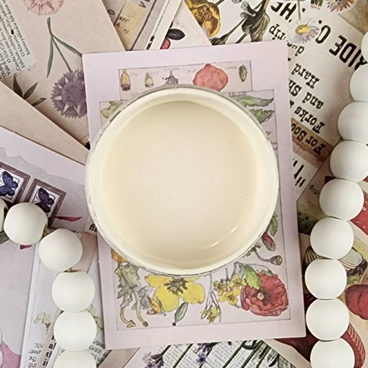 Image of open jar of creamy beige colored paint on colorful postcards in background.