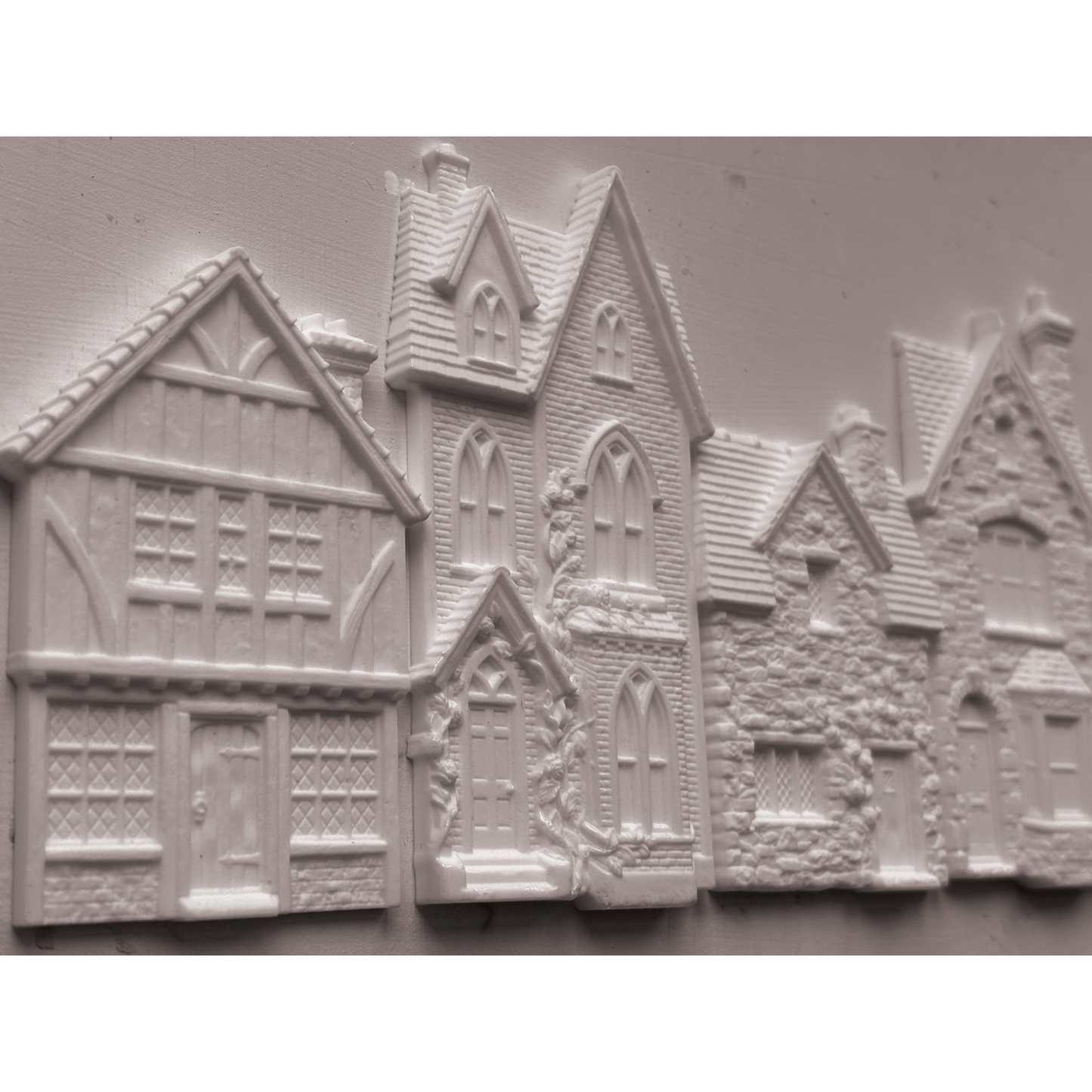 Unpainted castings of houses with detailed medieval and cottage architecture, shown on a plain light background.