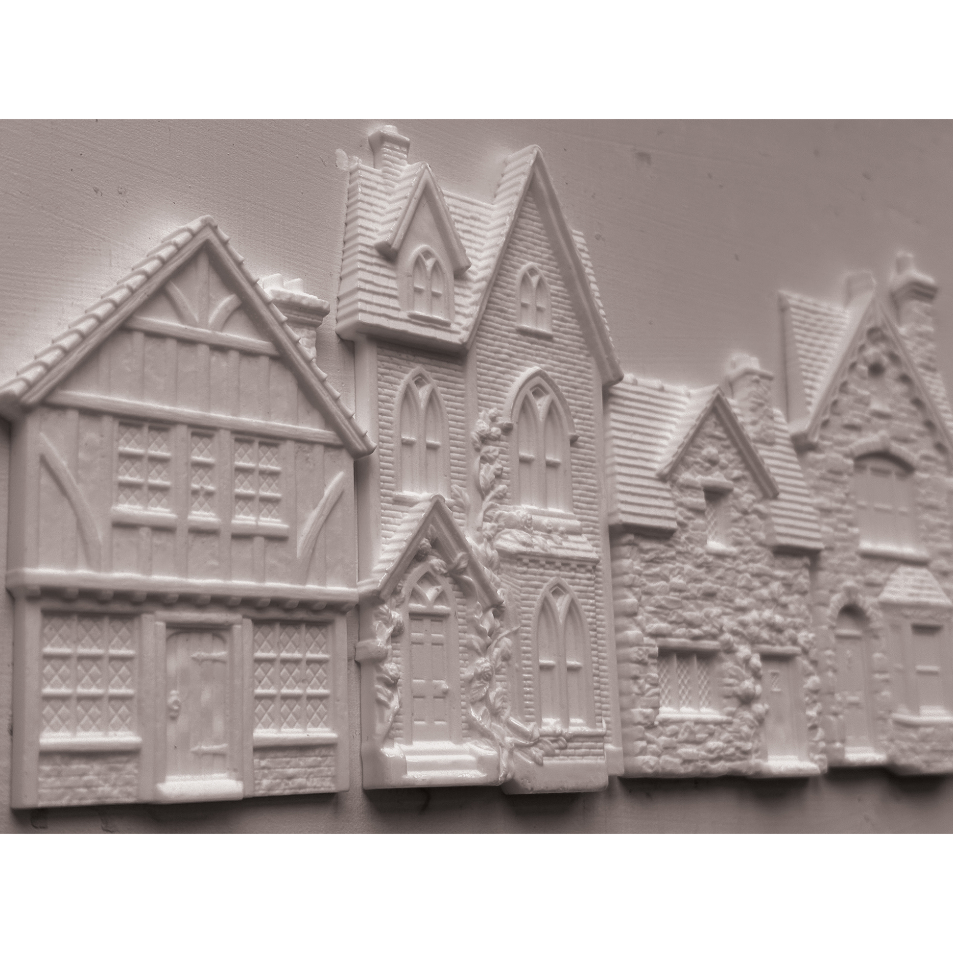 Unpainted castings of houses with detailed medieval and cottage architecture, shown on a plain light background.