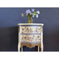 Decorative chest of drawers with floral and bird patterns against a dark blue background
