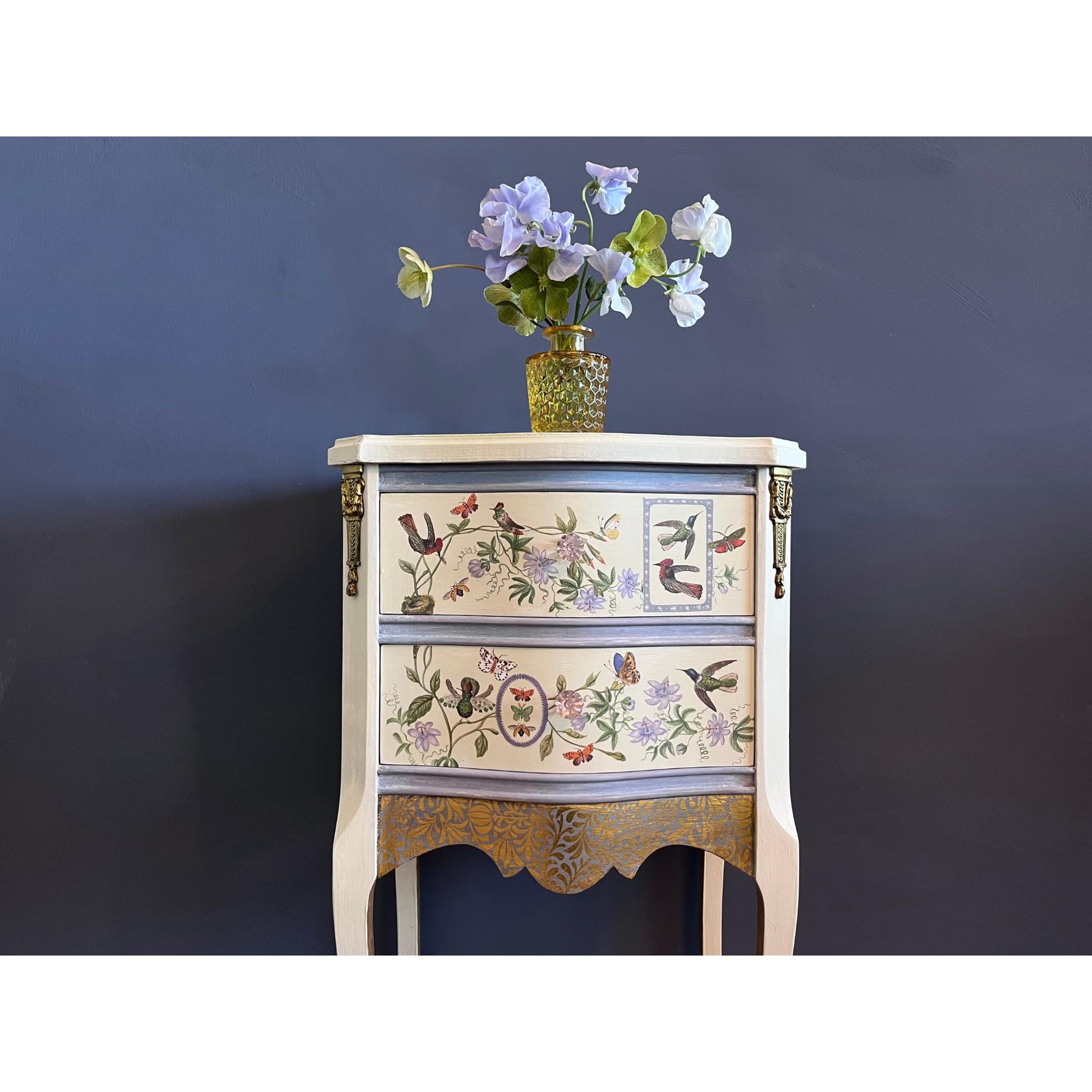 Decorative chest of drawers with floral and bird patterns against a dark blue background