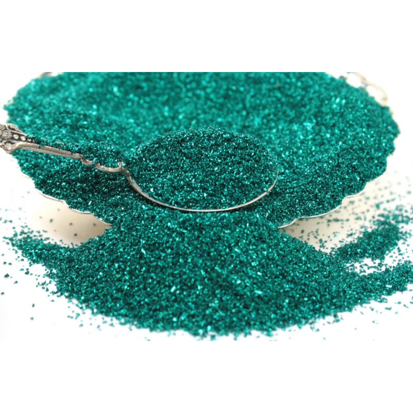 Green glitter on a white background with a spoon