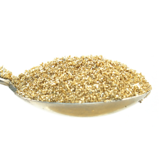 Spoon filled with gold-colored glitter on a white background