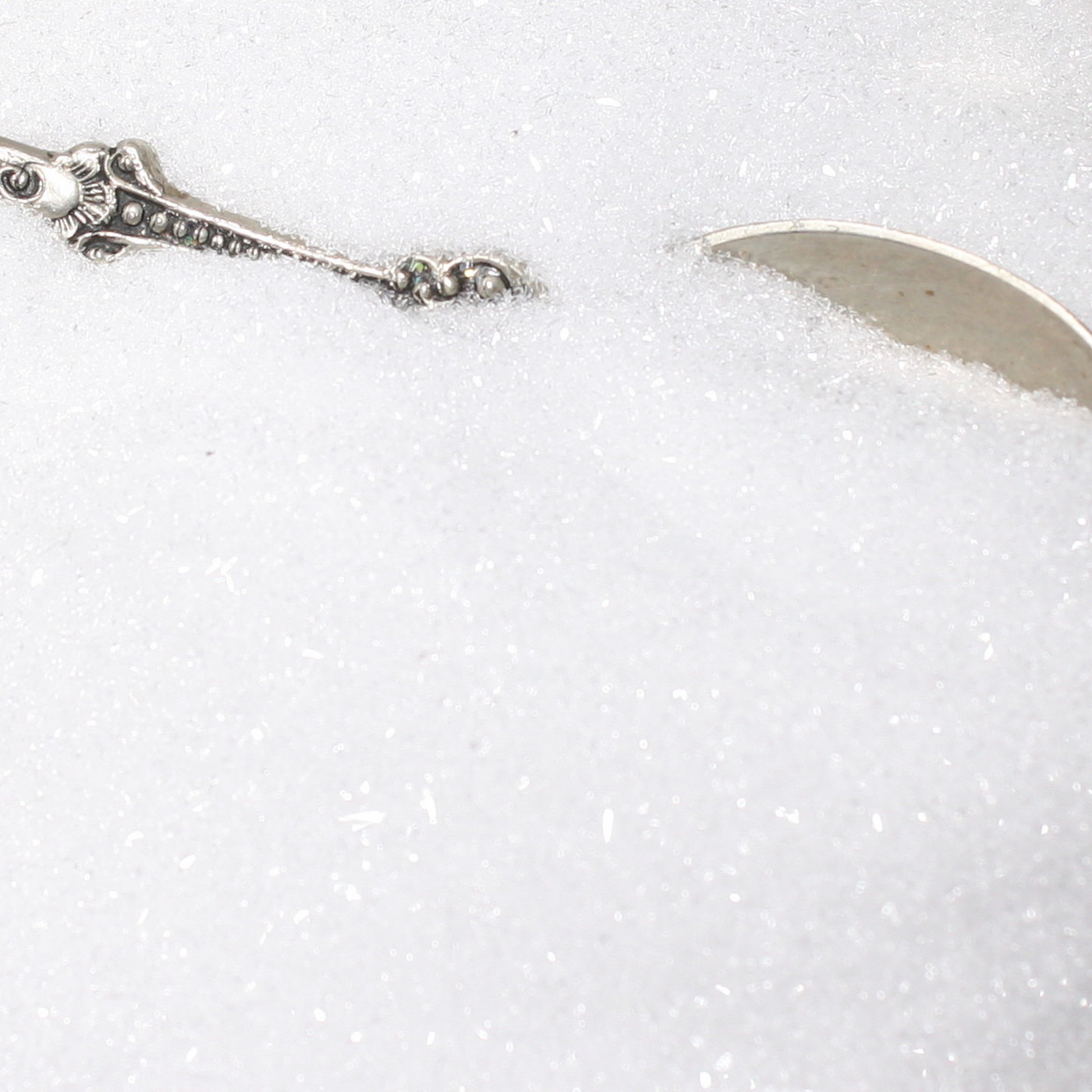 Silver spoon partially submerged in white glitter