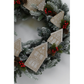 A festive Christmas wreath with frosted green pine branches, red berries, pinecones, and hanging gingerbread house ornaments on a light gray background.