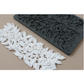 A dark gray rectangular silicone mold with embossed floral leaf patterns, shown next to a long strip of white molded floral leaf trim on a beige background.