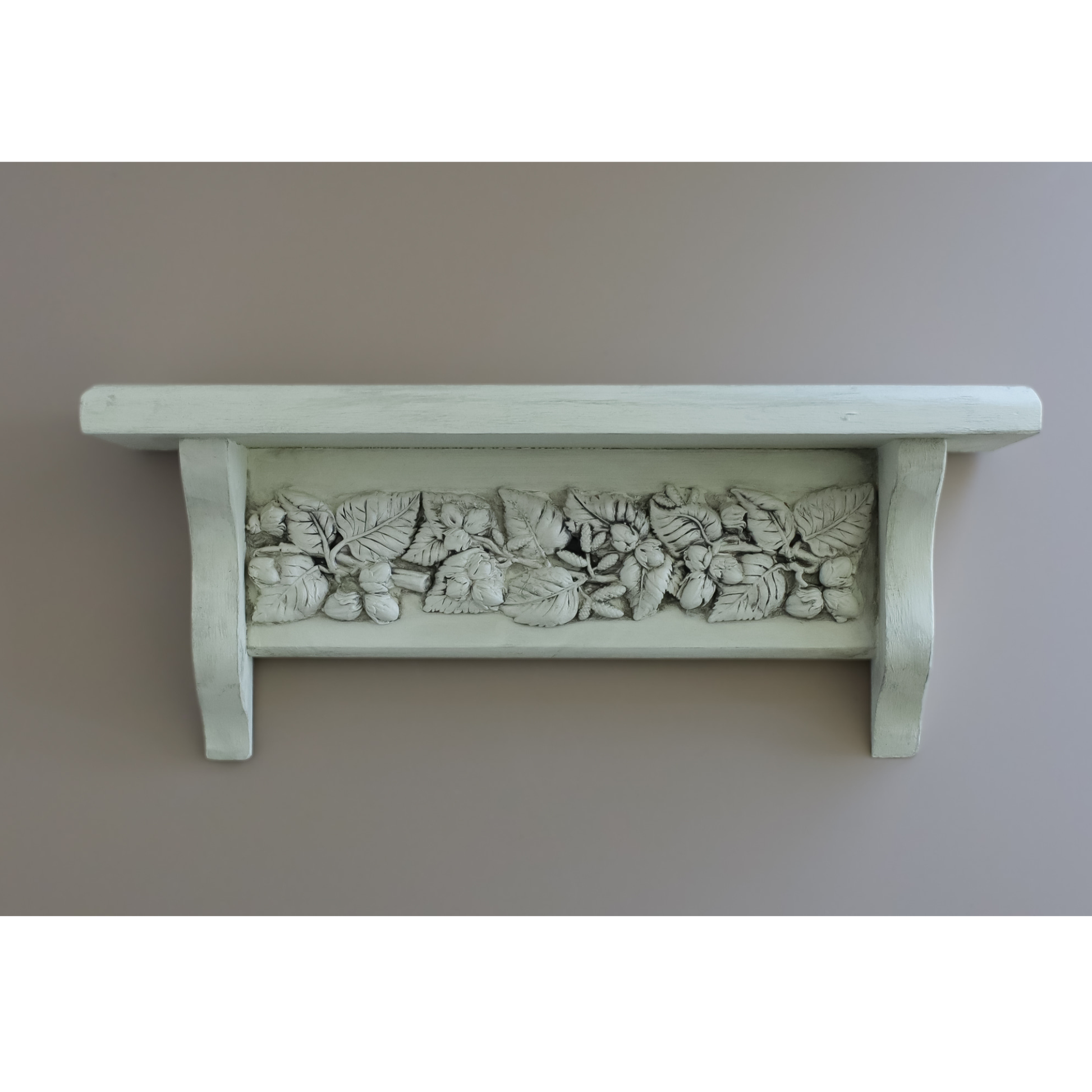 A white-painted wooden shelf with a detailed relief carving of grapes and leaves across the front, mounted against a plain taupe wall.