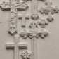 Decorative white crosses castings with intricate designs on a light gray background
