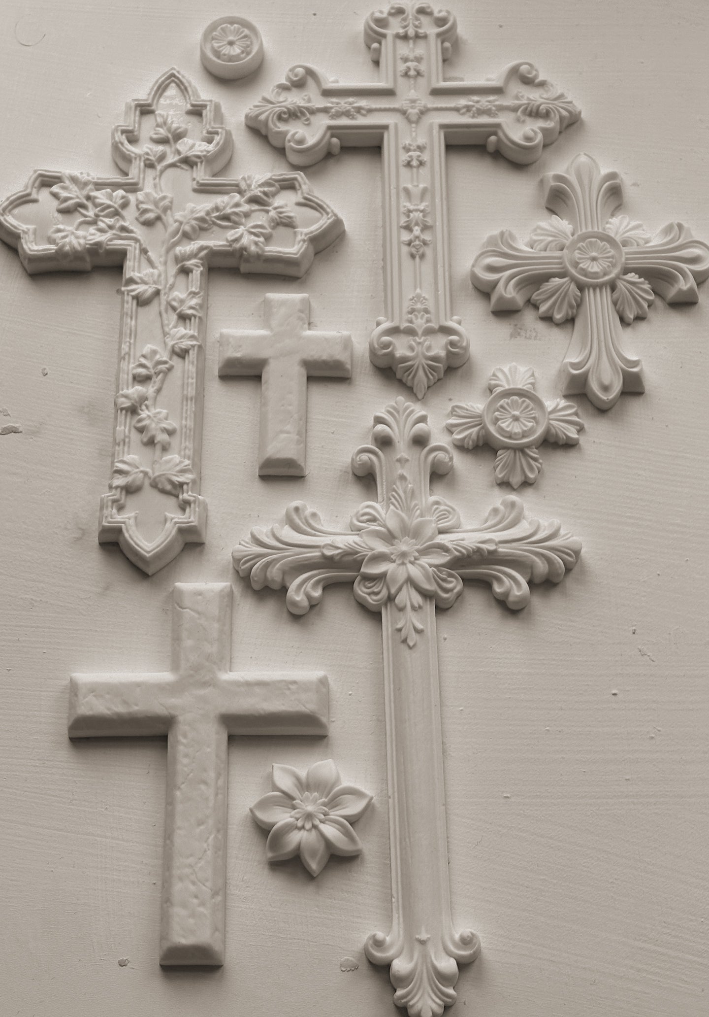 Decorative white crosses castings with intricate designs on a light gray background