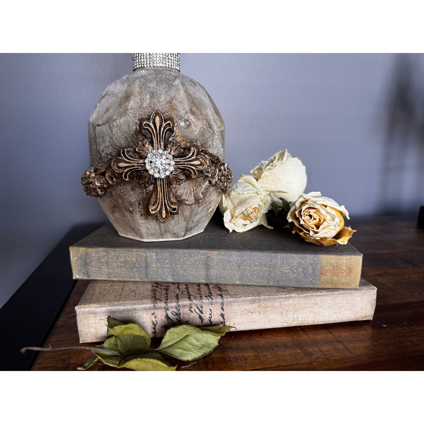 Decorative stone with cross and crystal on a stack of books with flowers