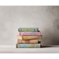 Stack of colorful books with decorated spines on a neutral background