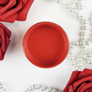 Image of an open jar of bright red paint with red roses and pearls in the background.