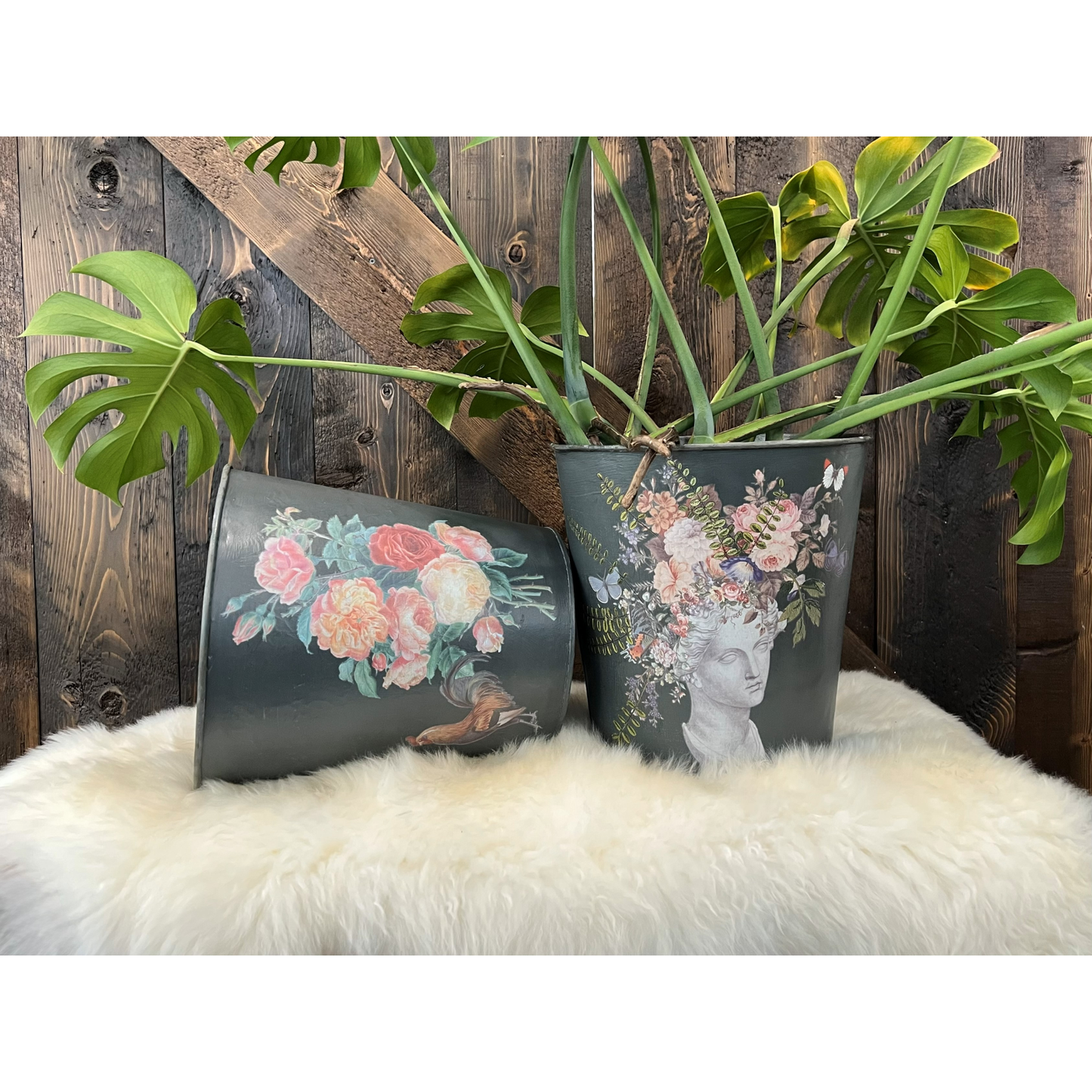 Two black planters with floral designs on a wooden background