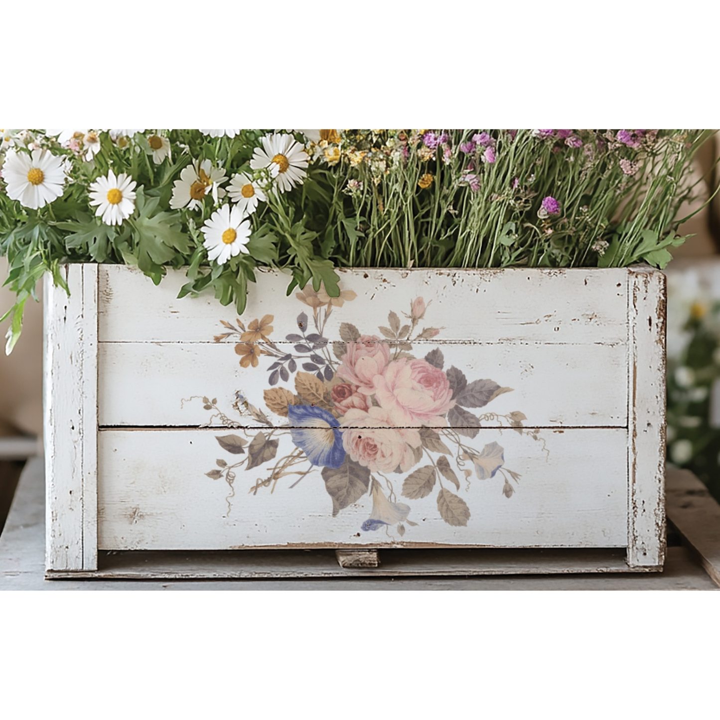 Decorative wooden planter with floral design and plants on a white background