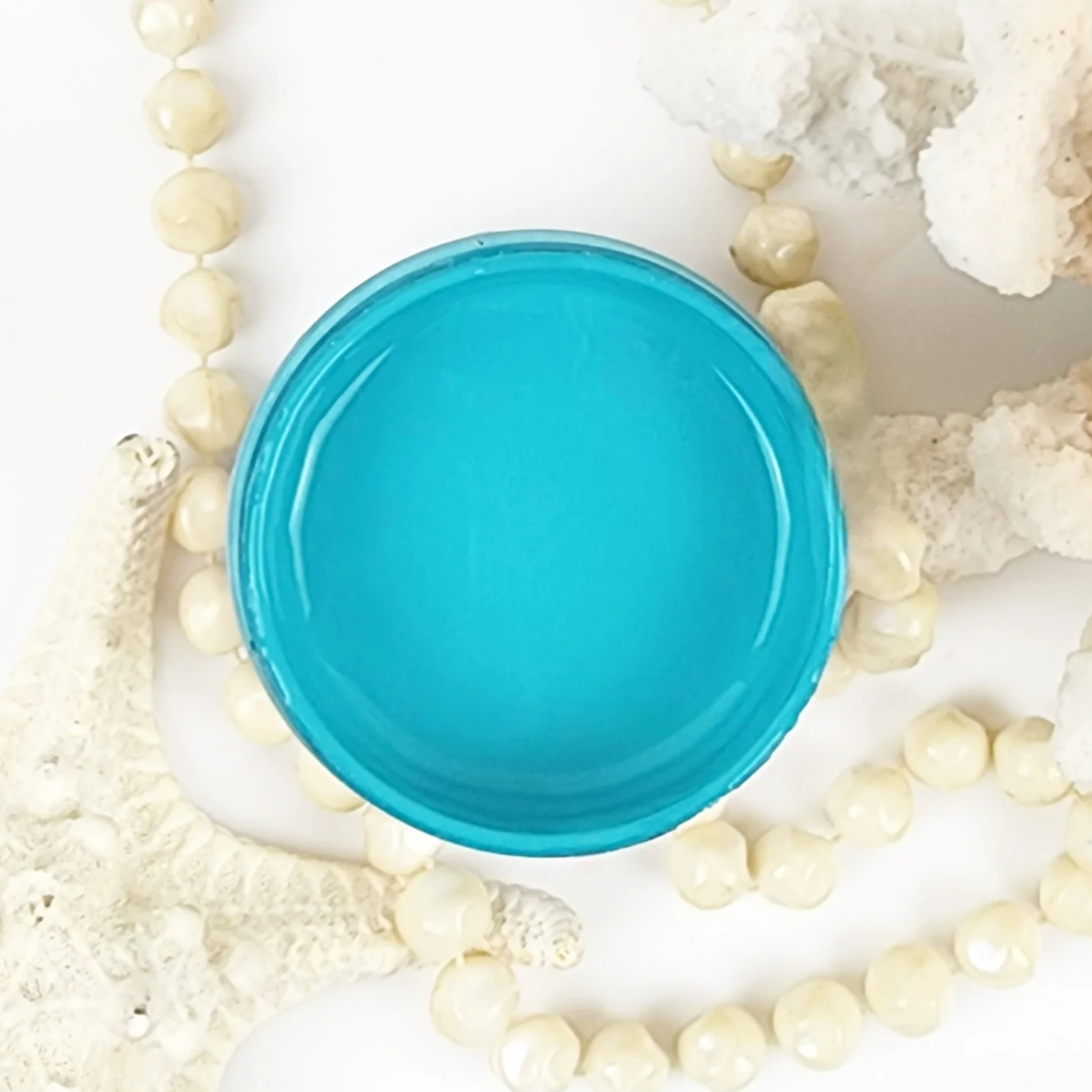 Image of an open jar of bright turquoise paint.
