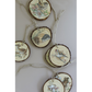 A variety of round natural wood slices with rustic bark edges, each decorated with different woodland animal IOD transfer images such as a bird, hedgehog, deer, rabbit, and squirrel. The slices are strung together with light twine on a plain light gray background.