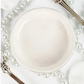 Open jar of off-white metallic paint against a white background with pearls and silverware.