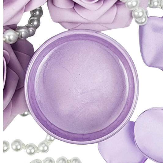 Open jar of light purple metallic paint with pearls and rose petals.
