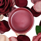 Open paint jar with deep pink metallic paint surrounded by red and pink roses on a white background