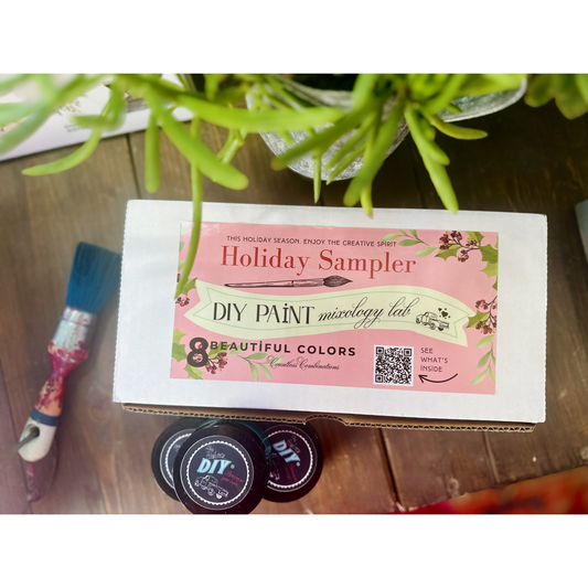 DIY paint sample set with a brush and plant on a wooden surface